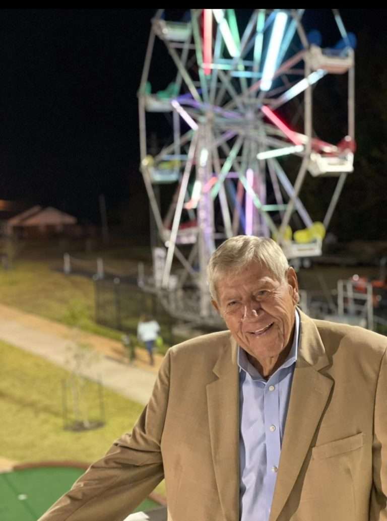 Previous owner of Atoka Railroad Adventure Mr. Brown, with Ferris wheel in the background